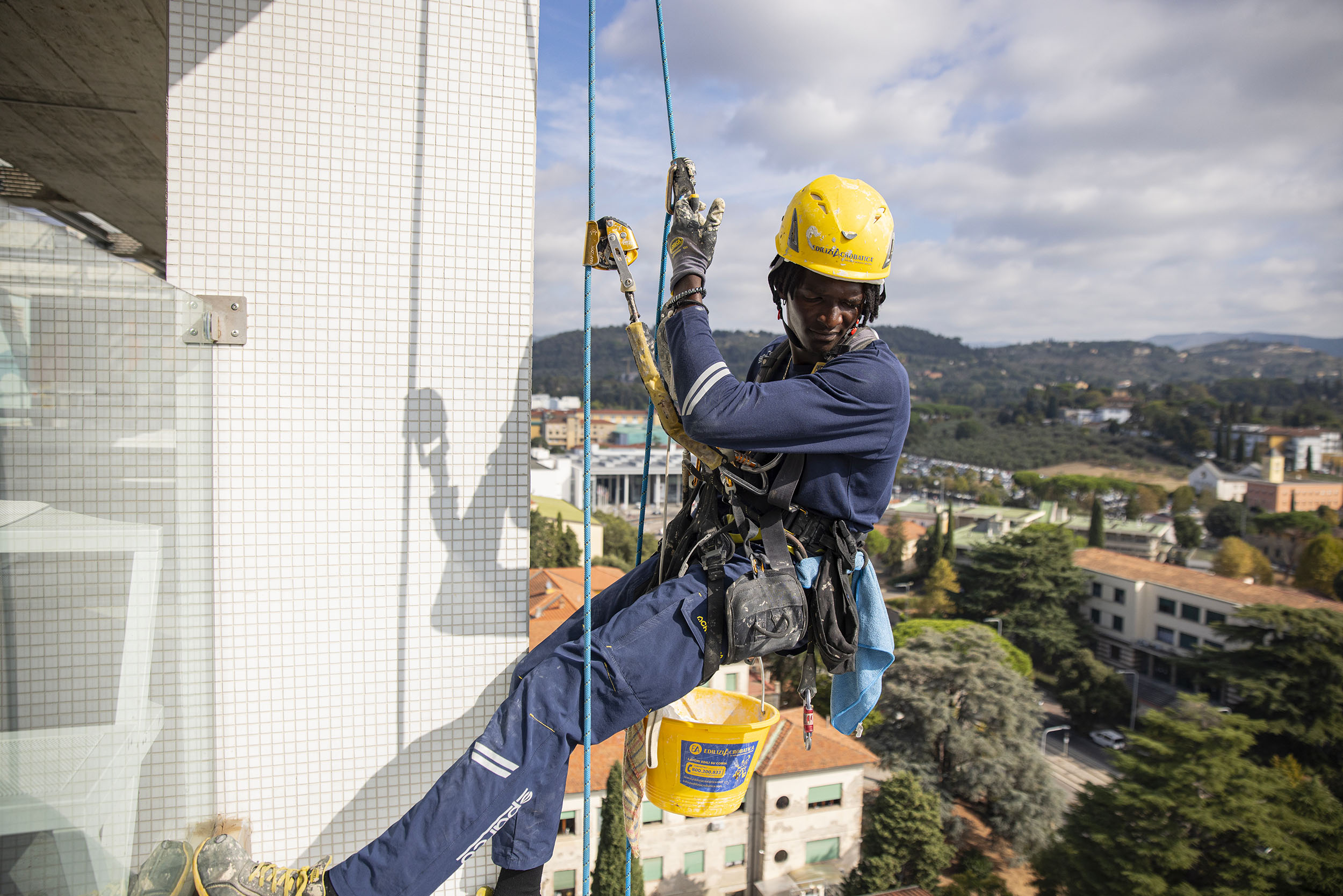 Operatore su fune con i dispositivi di sicurezza al lavoro sulla facciata di un edificio