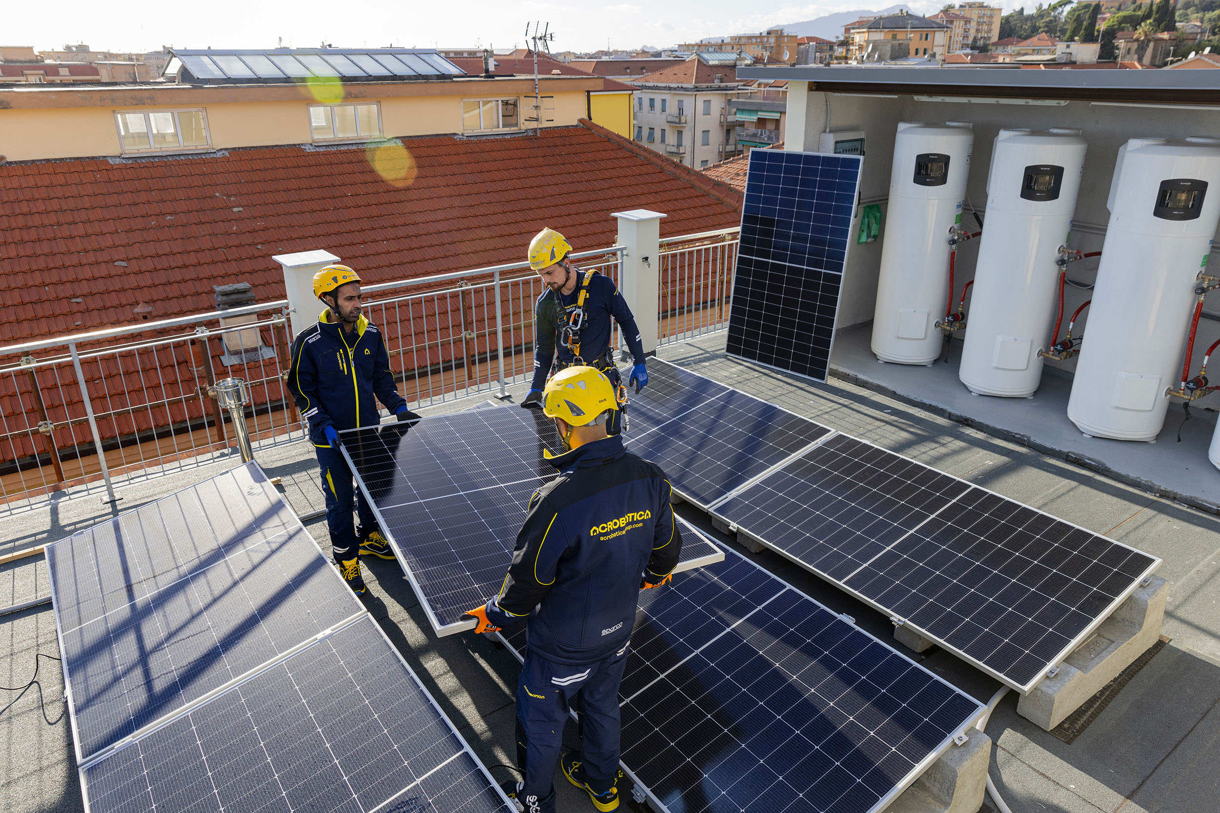 Tre tecnici Acrobatica Energy installano pannelli fotovoltaici su un tetto